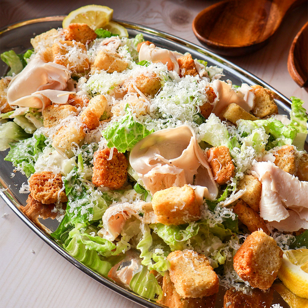 Salade césar avec de la poitrine de dinde Smart & Natural dans une assiette en aluminium avec cuillère en bois