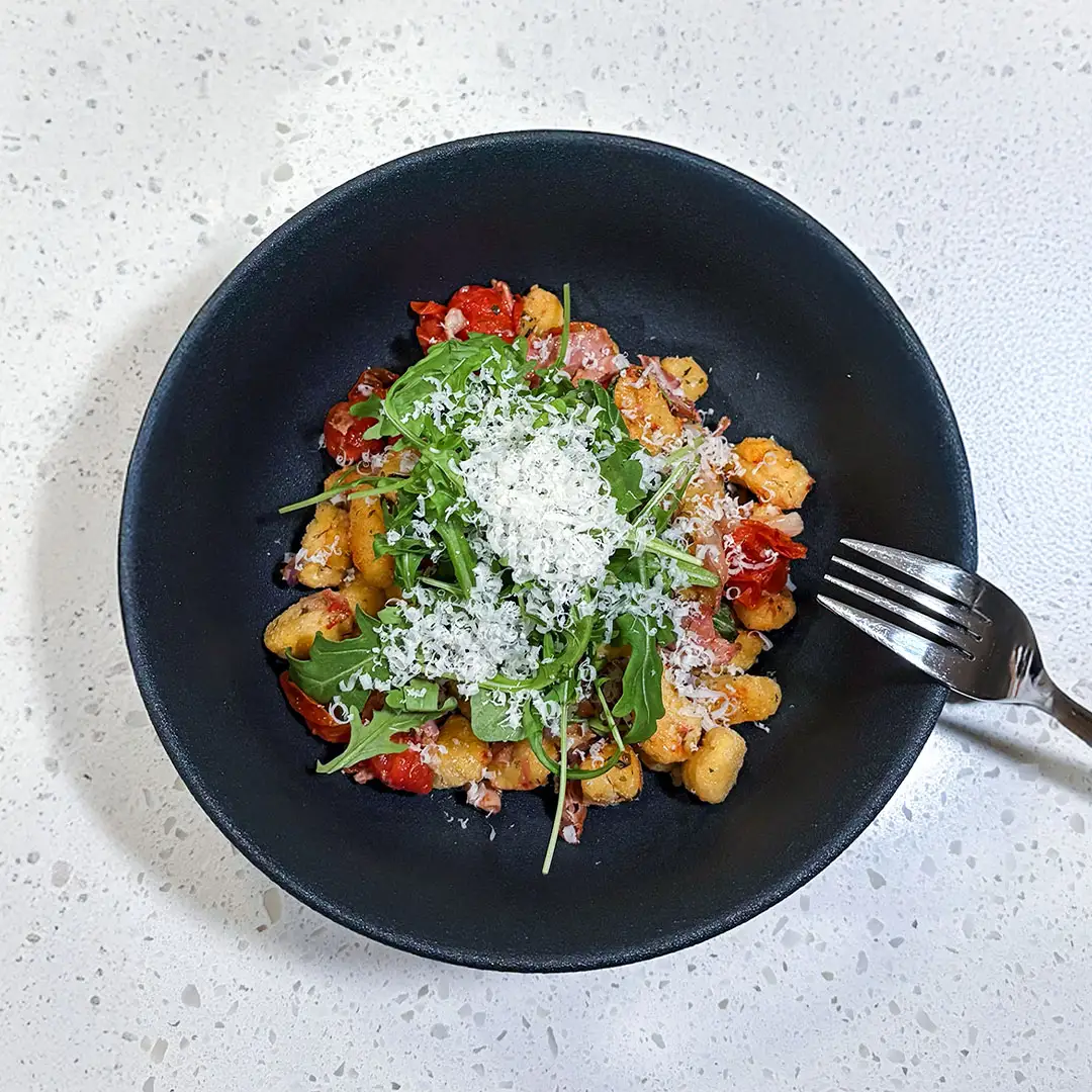 Gnocchis rôtis au jambon fumé forêt noire Smart & Natural avec de la roquette et du parmesan dans un bol noir