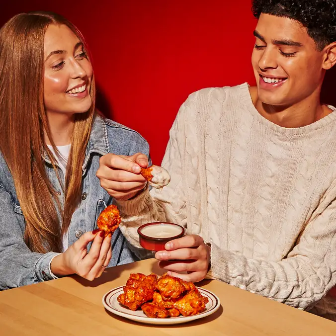 Des amis mangeant des ailes de poulets