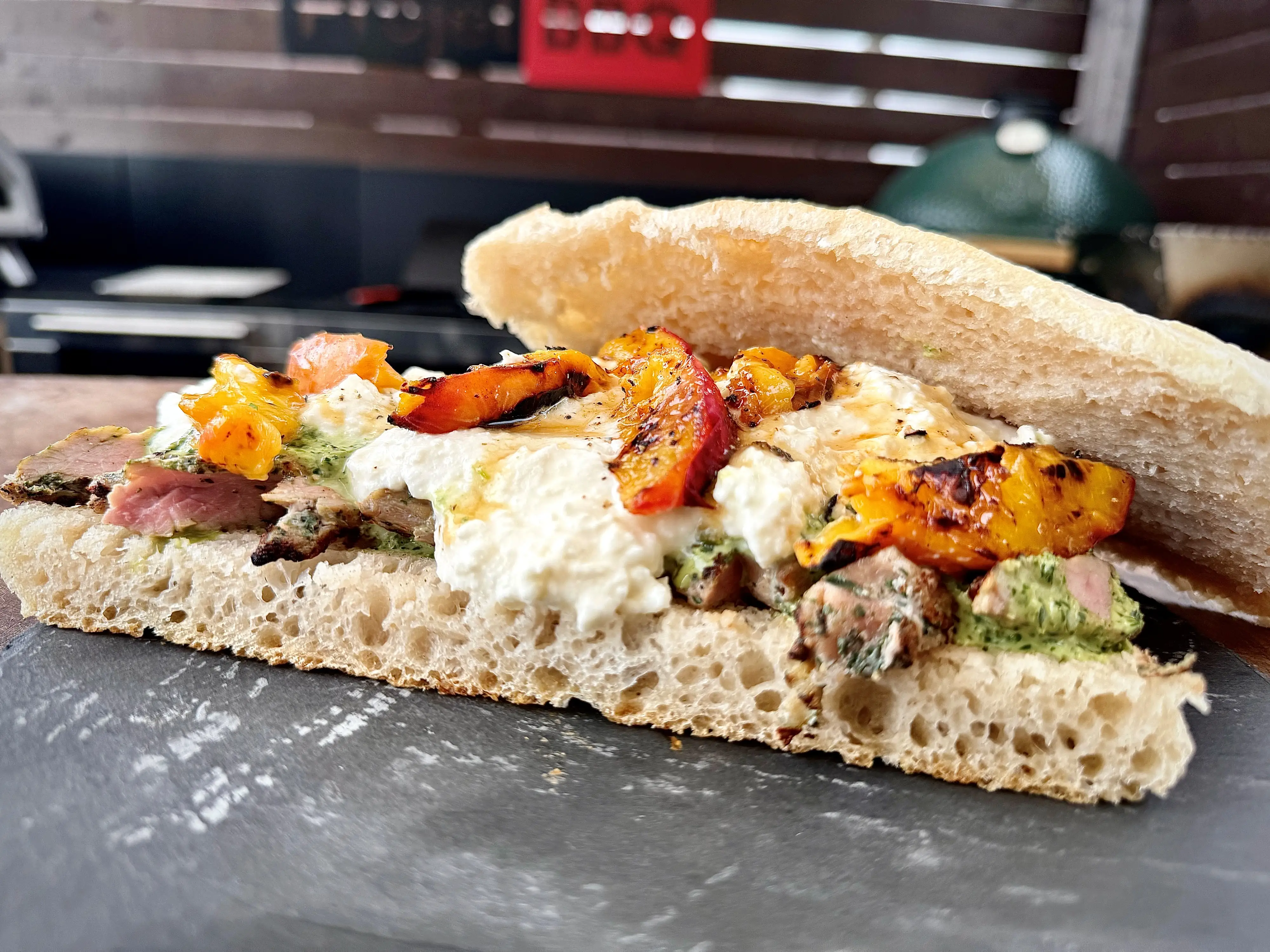 Sandwich ouvert avec viande grillée, fromage et pêches sur pain ciabatta