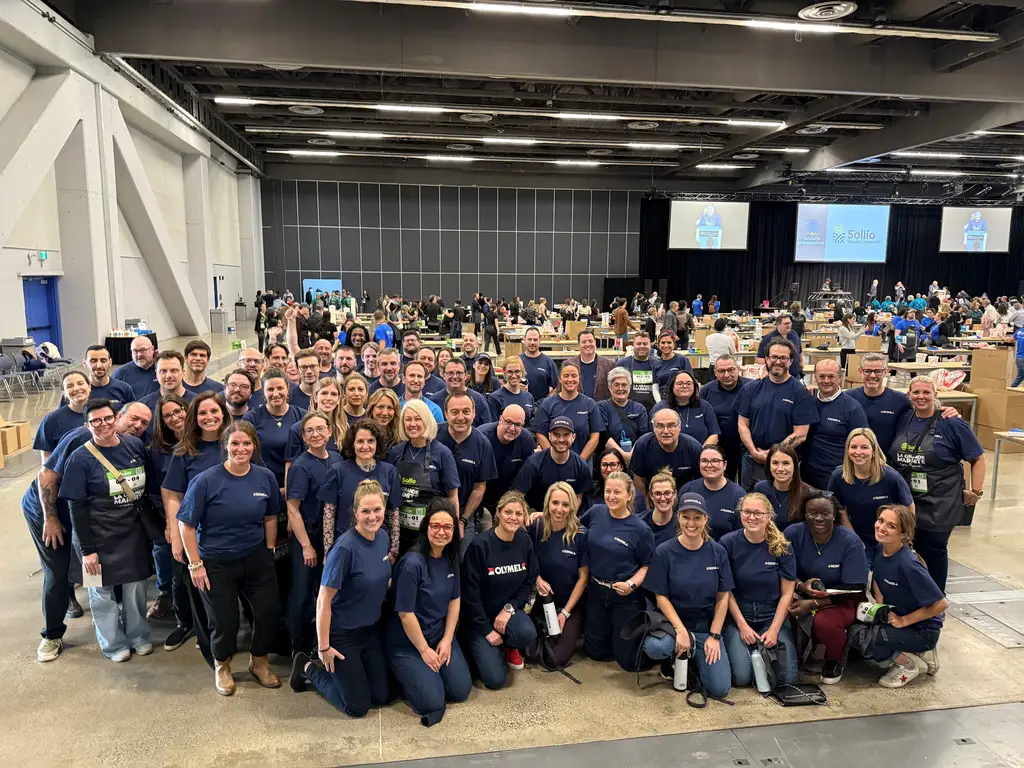 Un grand groupe de personnes portant des chemises bleues assorties pose pour une photo de groupe dans un vaste lieu intérieur.