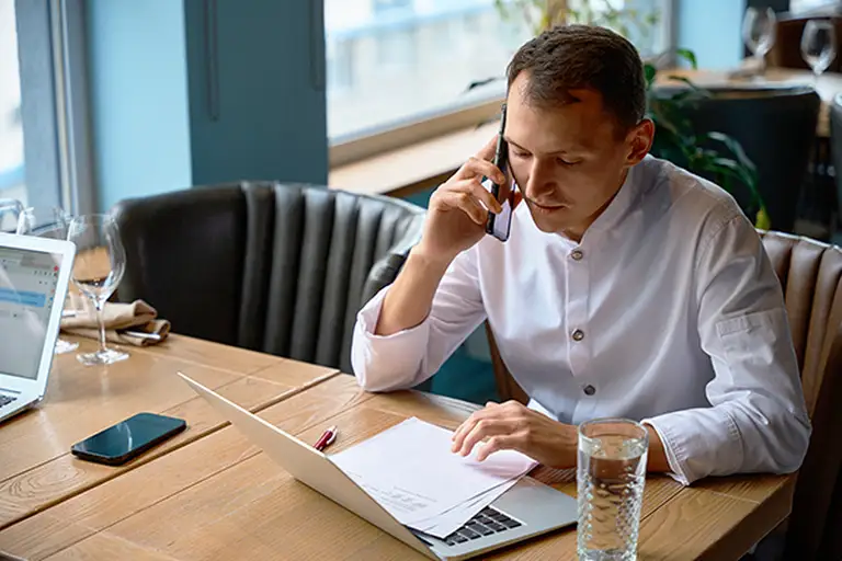 Homme au téléphone et devant son laptop