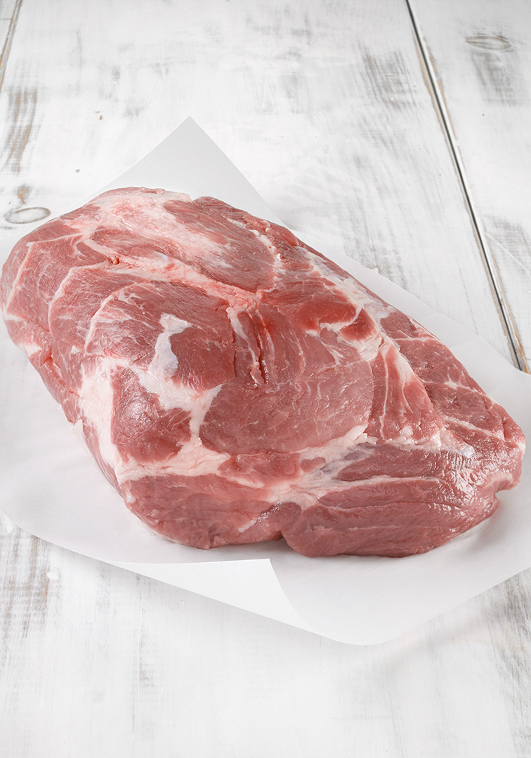 Morceau de porc cru sur papier blanc, fond en bois clair.