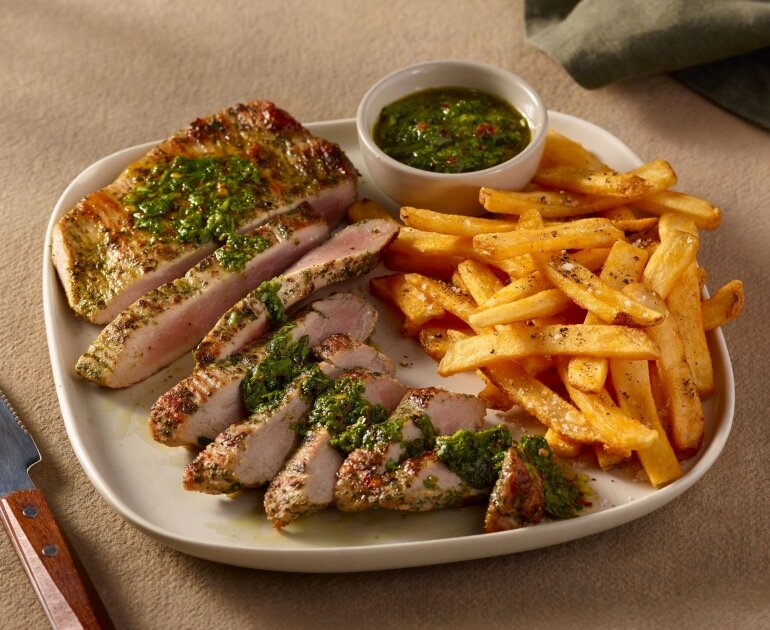 Tranches de viande grillée avec sauce verte, frites et sauce supplémentaire.