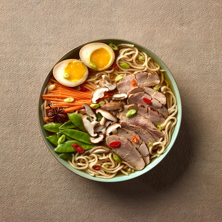 bol ramen avec filet de porc miel et ail, nouilles, champignons, oeufs, carottes et pois verts