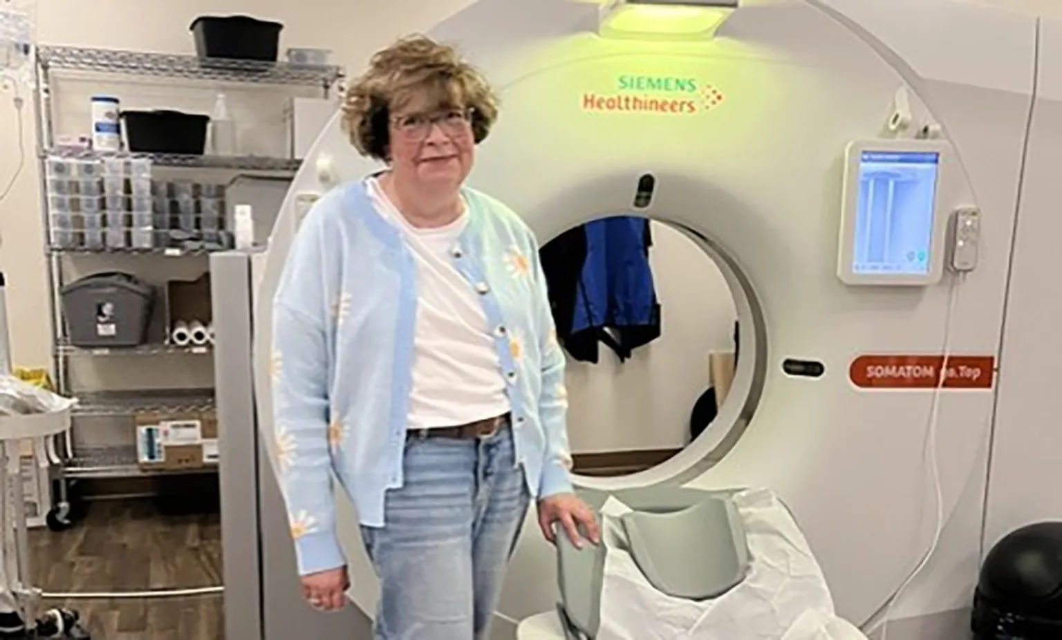 Heather Thiessen debout à côté d’un appareil de tomodensitométrie dans une salle d’imagerie médicale.