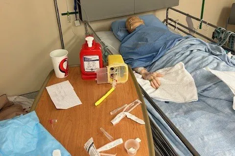 Salle d’évasion reproduisant une chambre d’hôpital. Un mannequin est couché dans le lit, entouré d’objets et d’emballages représentant des risques potentiels pour la sécurité des patients.